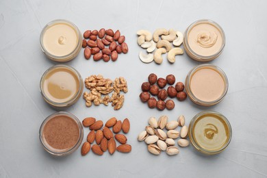 Photo of Different types of delicious nut butters and ingredients on grey table, flat lay