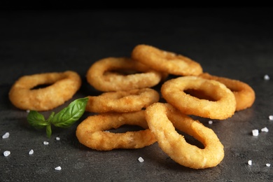 Fried onion rings and basil leaves on grey table