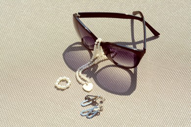 Stylish sunglasses and jewelry on grey surface