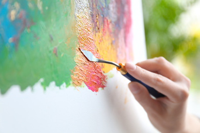 Artist painting on canvas with spatula, closeup