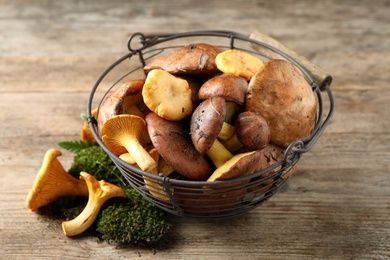 Basket with different wild mushrooms on wooden table
