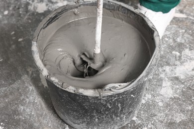 Worker mixing concrete in bucket indoors, closeup