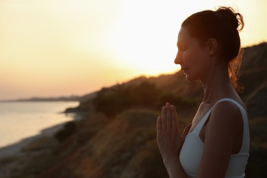 Photo of Mature woman meditating outdoors in evening. Space for text