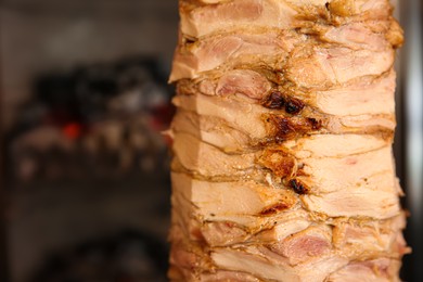 Photo of Vertical rotisserie with roasted meat, closeup view. Space for text
