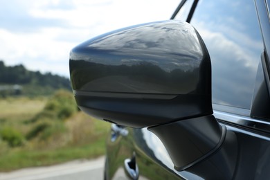New black modern car outdoors, closeup of side rear view mirror