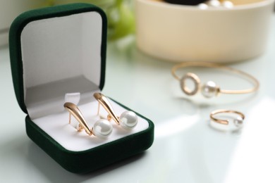 Elegant golden earrings in box on white table, closeup view