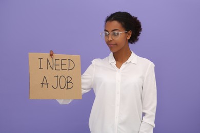 Photo of Unemployed African American woman holding sign with phrase I Need A Job on violet background