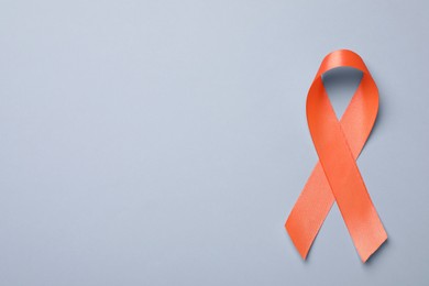 Orange ribbon on light grey background, top view with space for text. Multiple sclerosis awareness