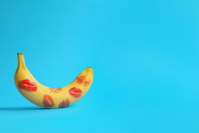 Banana covered with red lipstick marks on light blue background, space for text. Potency concept