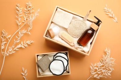 Eco friendly products in crates on pale orange background, flat lay