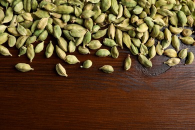 Dry cardamom pods on wooden table, top view. Space for text