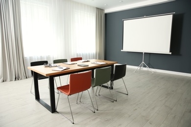 Modern meeting room interior with large table and projection screen