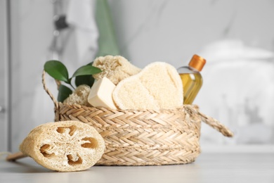 Photo of Natural loofah sponge near wicker basket on table in bathroom