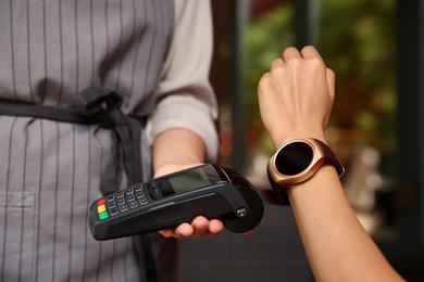 Photo of Woman making payment with smart watch outdoors, closeup
