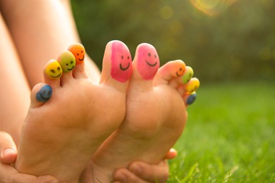 Teenage girl with smiling faces drawn on toes outdoors, closeup