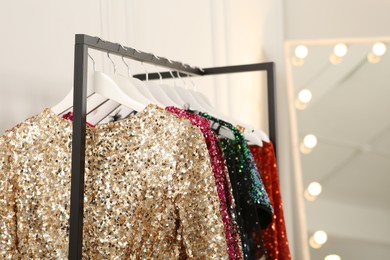 Photo of Clothing rack with colorful sequin party dresses on hangers in boutique, space for text
