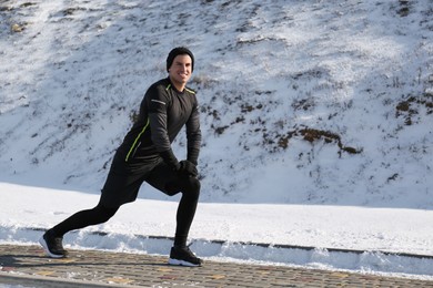Man doing sports exercises outdoors on winter day. Space for text