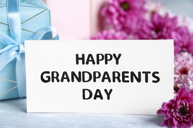 Beautiful flowers, gift boxes and card with phrase Happy Grandparents Day on grey table, closeup