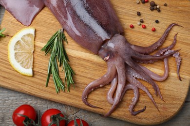 Fresh raw squid with lemon, rosemary and tomatoes on wooden table, flat lay