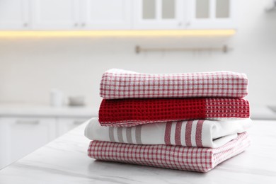 Stack of different clean towels on white table in kitchen