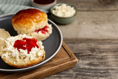 Photo of Freshly baked soda water scones with cranberry jam and butter on wooden table, closeup. Space for text