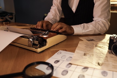 Old fashioned detective working with typewriter at table in office, closeup