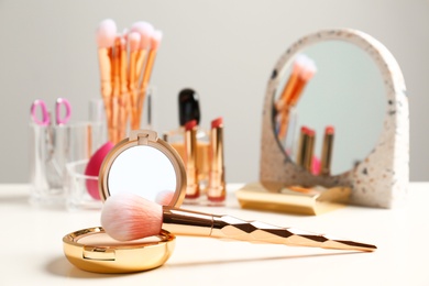 Compact powder and makeup brush on dressing table. Space for text