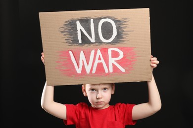 Boy holding poster No War against black background