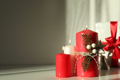 Burning candles with Christmas decor on white table. Space for text