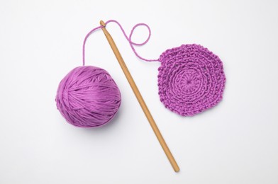Soft violet woolen yarn, knitting and crochet hook on white background, top view