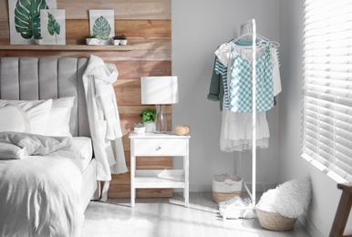 Stylish bedroom interior with clothing rack and large window