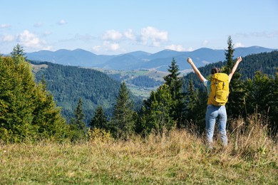 Tourist with backpack in mountains on sunny day, back view