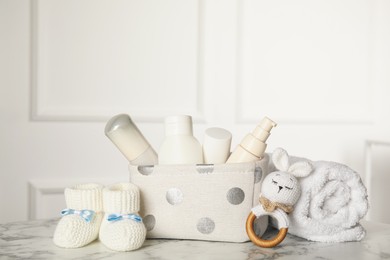 Baby booties and accessories on white marble table indoors. Space for text