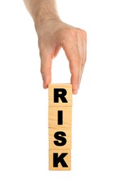 Man stacking wooden cubes with word Risk on white background, closeup