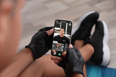 Man having workout with personal trainer via smartphone at home, closeup