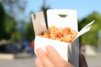 Woman holding paper box with takeaway noodles outdoors, closeup and space for text. Street food
