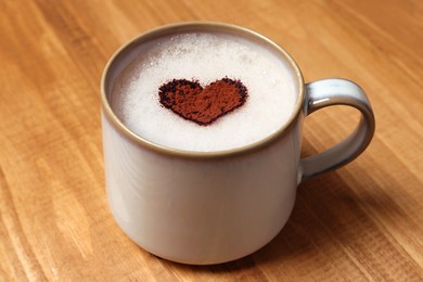 Photo of Mug of aromatic coffee with heart shaped decoration on wooden table