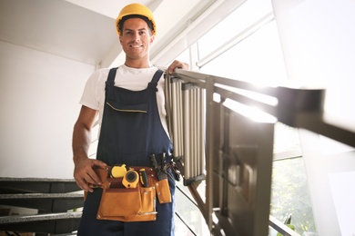 Professional builder carrying metal ladder down stairs