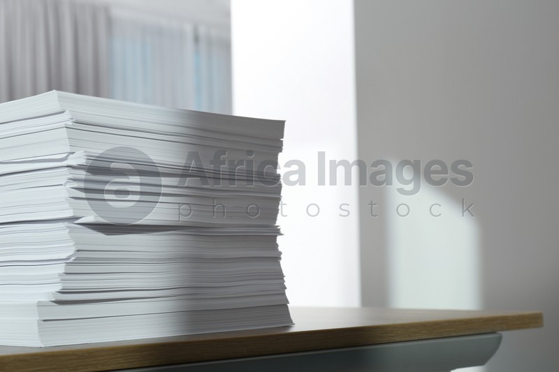 Stack of paper sheets on wooden table indoors. Space for text
