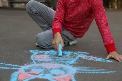 Child drawing cat with chalk on asphalt, closeup