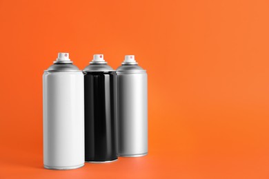 Cans of spray paints on orange background. Space for text