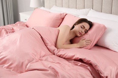 Young woman sleeping in comfortable bed with silky linens