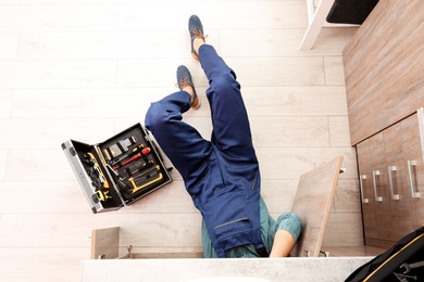 Male plumber repairing kitchen sink, top view