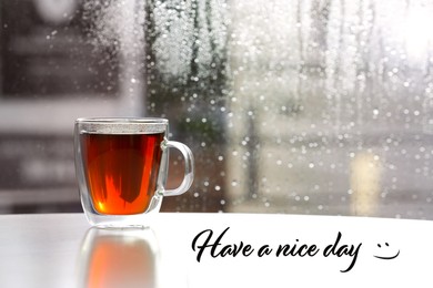 Cup of fresh hot tea on windowsill and text Have a nice day