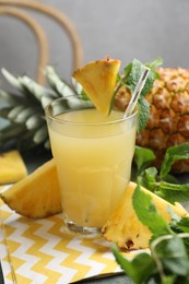 Photo of Delicious pineapple juice in glass and fresh fruit on table