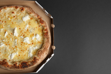 Delicious cheese pizza in takeout box on black background, top view. Space for text
