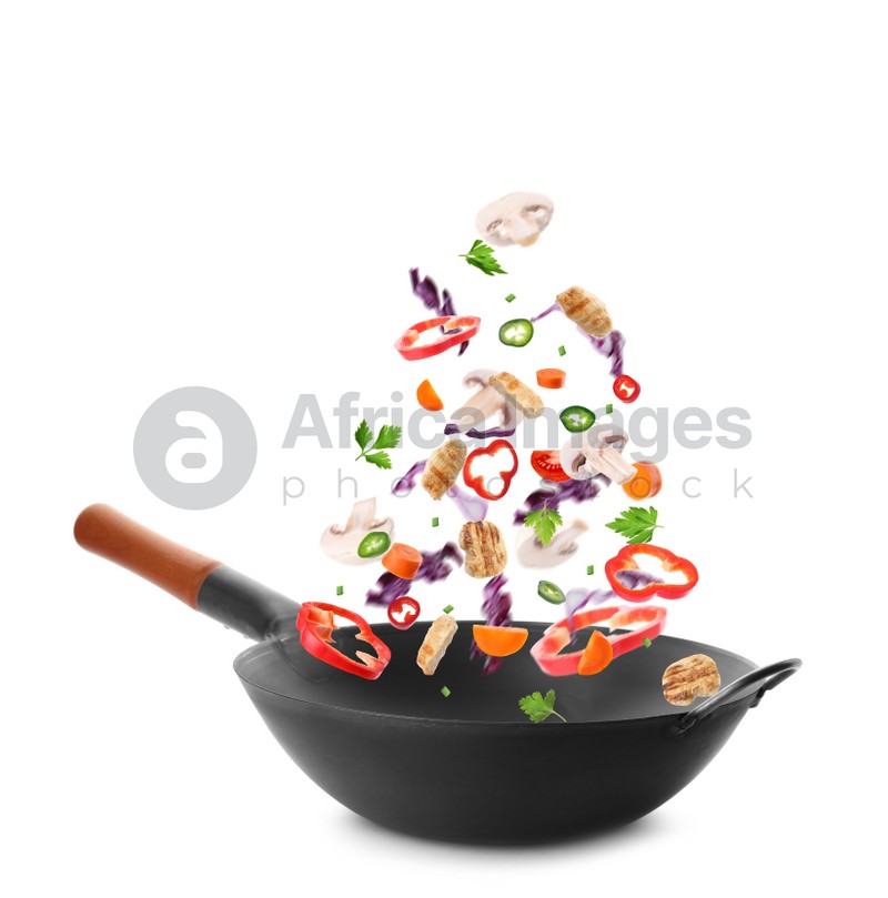 Different tasty ingredients falling into wok on white background