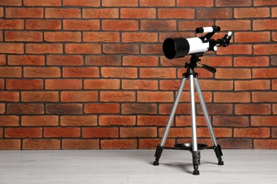 Photo of Tripod with modern telescope near brick wall. Space for text
