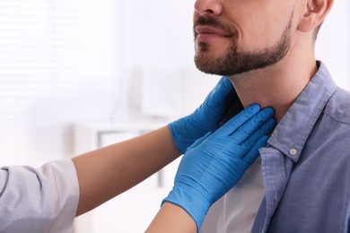 Doctor examining thyroid gland of patient in hospital, closeup