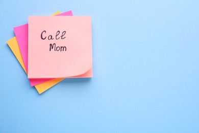 Photo of Paper note with phrase Call mom on light blue background, top view. Space for text